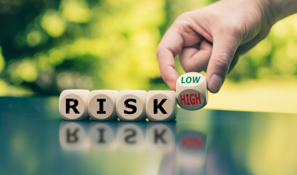 Symbol for reducing a risk. Cubes form the word "RISK" while a hand turns a cube and changes the word "high" to low"