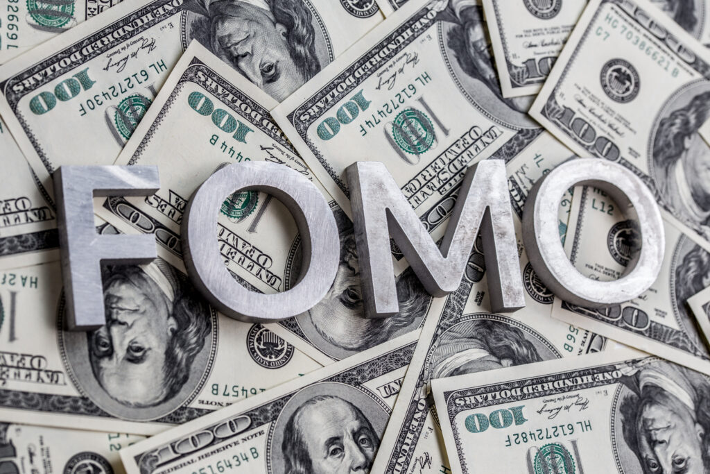 The word FOMO - fear of missing out - laid with aluminium letters on the US dollar banknotes background - with selective focus.