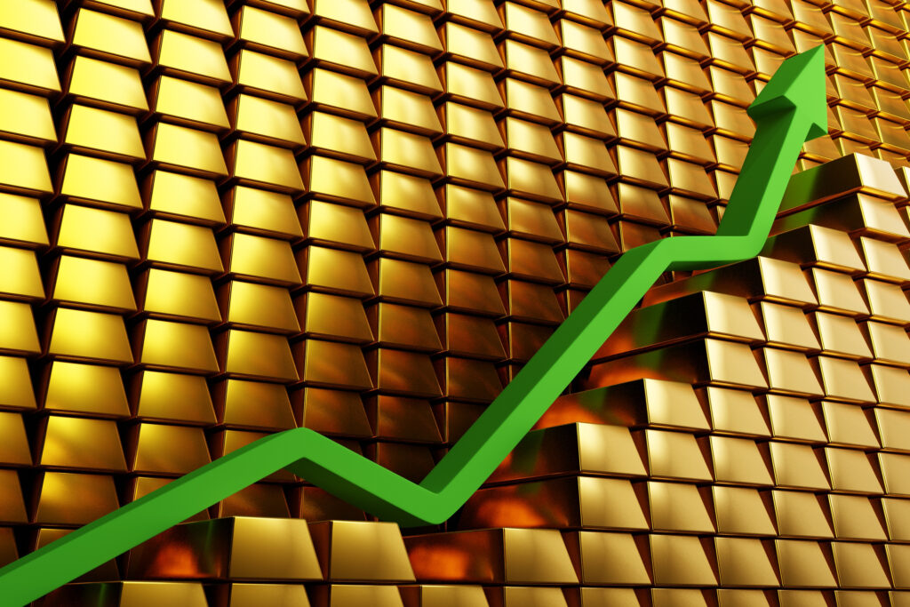 Gold prices soaring in a bullish market. Green arrow going up over gold bars. 