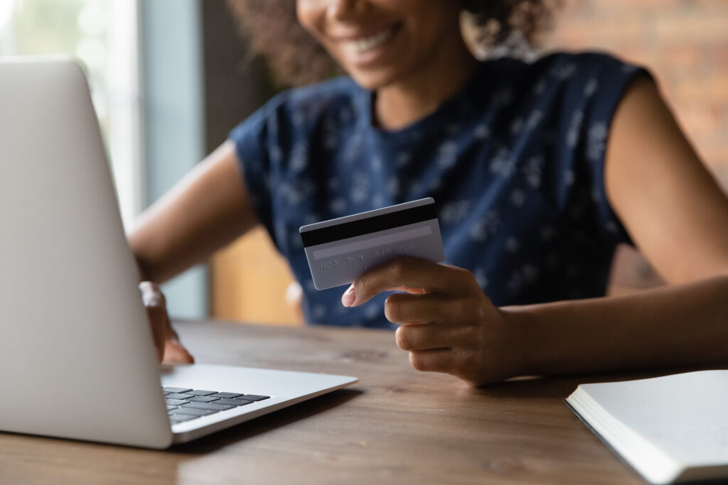 Close up of happy smiling young female shopper hold credit card pay online safe fast easy. client of electronic bank service make transaction using laptop web app