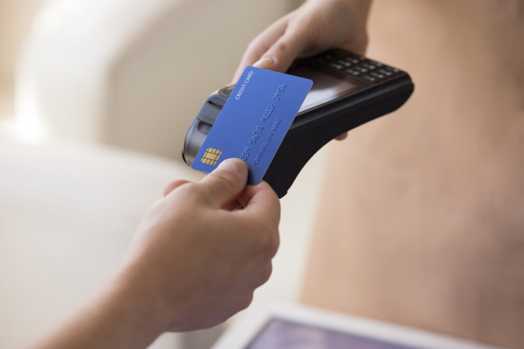credit cardholder paying bill, applying blue credit card with chip at wireless payment terminal, using electronic transaction banking technology. 