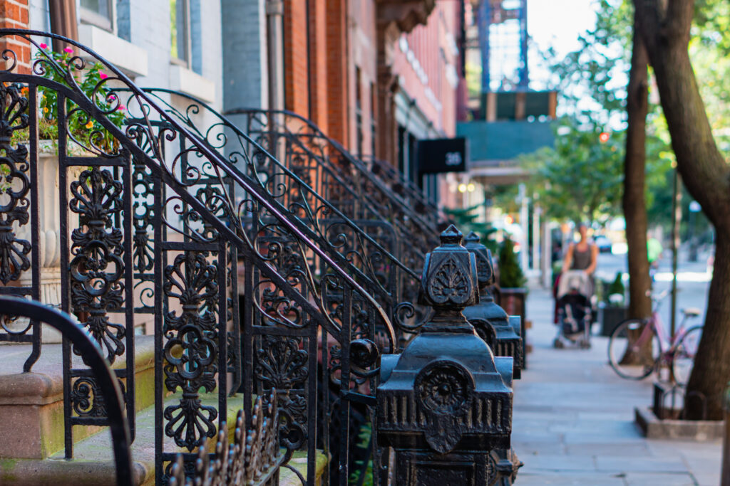 Classic red brick brownstone buildings with black iron railings in Greenwich Villages, Manhattan, New York City. Street scene.