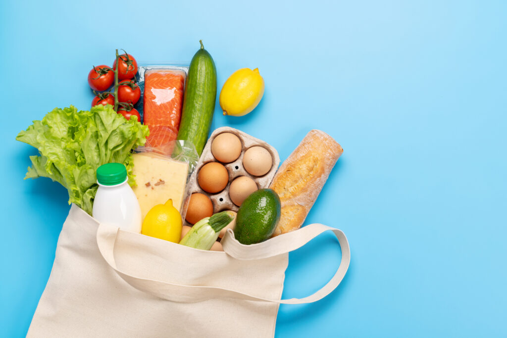 Shopping bag full of healthy food on blue background. everyday grocery purchases. 