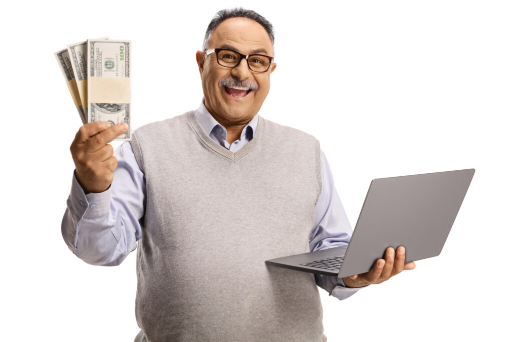 Excited mature man holding money and a laptop computer isolated on white background