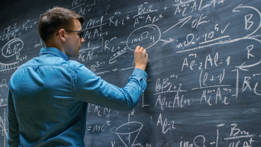 Brilliant Young man Approaches Big Blackboard and Finishes writing Sophisticated Formula/ Equation.