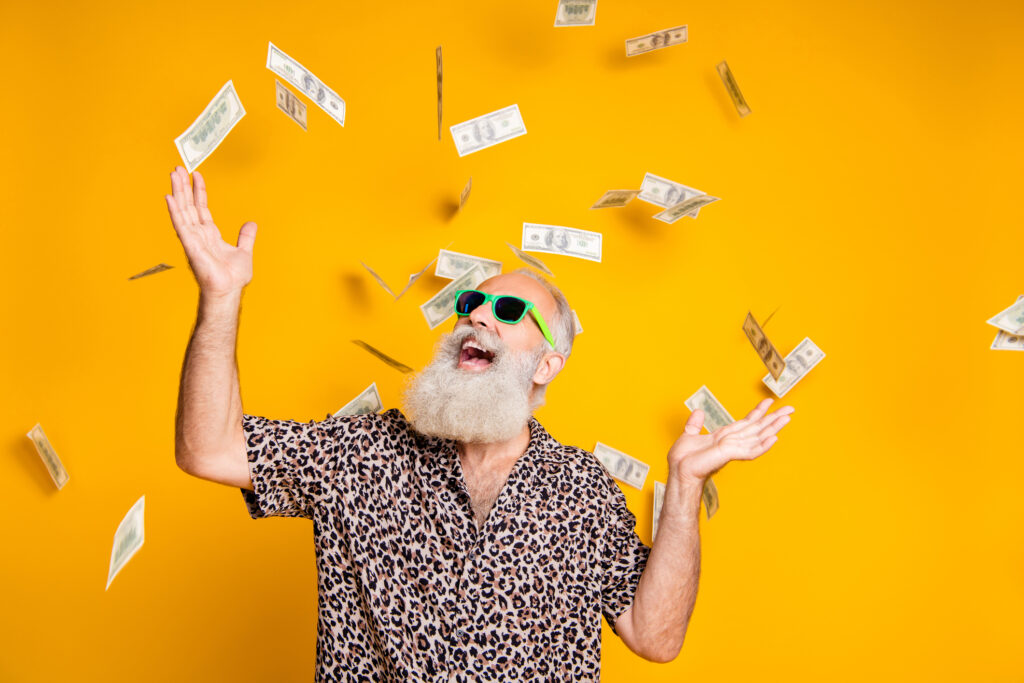 Portrait of crazy funky funny bearded man hipster in green eyeglasses, eyewear look up at money falling wearing leopard stylish shirt isolated over yellow background